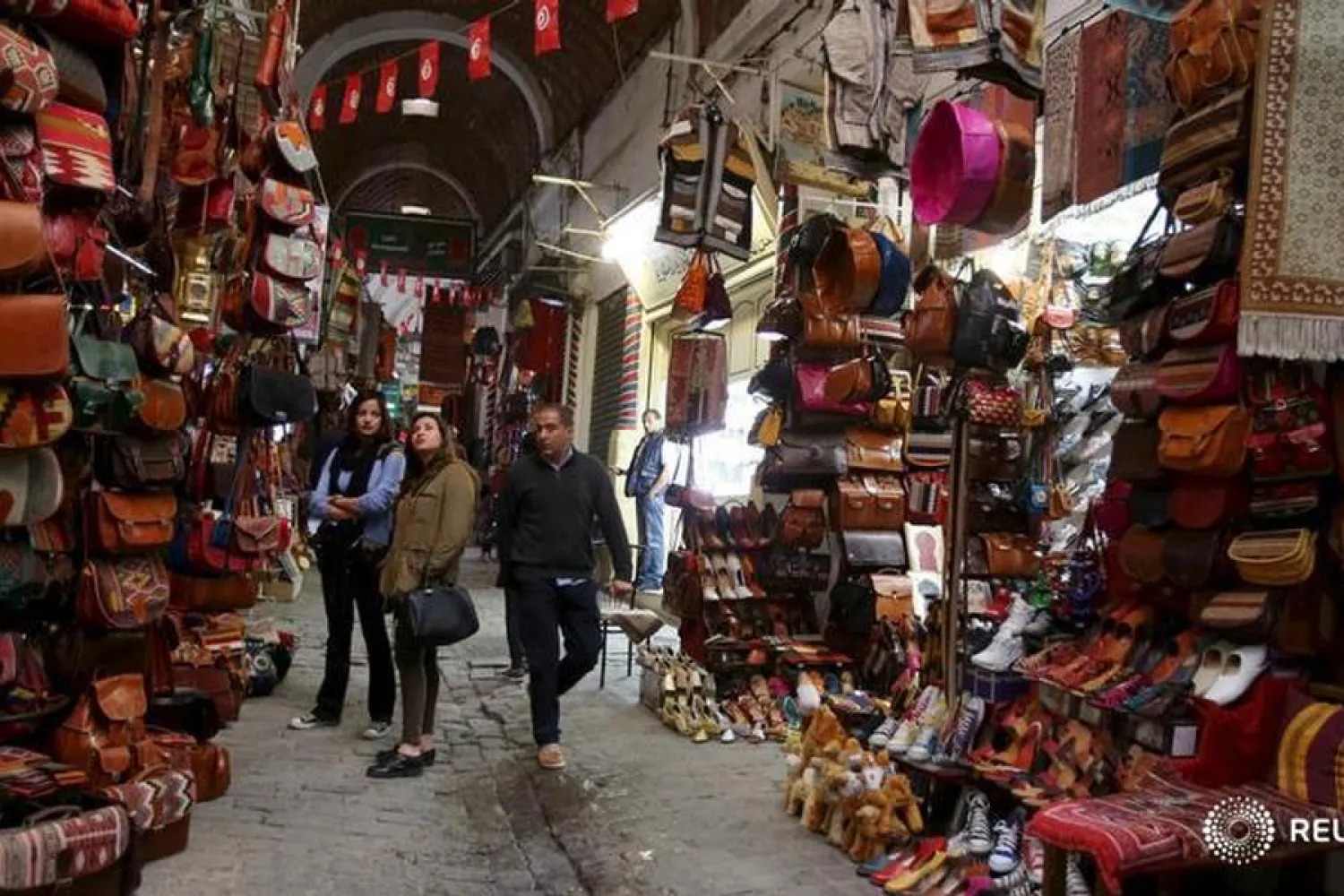 Tunisians walk near a souvenir shop in the medina in Tunis, Tunisia, April 2, 2016. REUTERS/Zoubeir Souissi