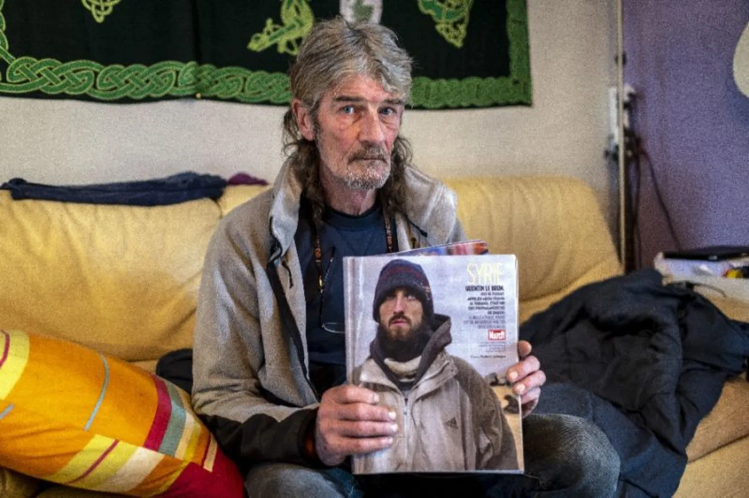 Jacques Le Brun holding a magazine picture of his son Quentin, who left to join ISIS in Syria in 2014, at the family home in Labastide-Rouairoux, southern France. (AFP)