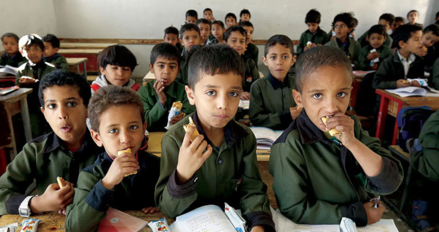 تلاميذ يتناولون بسكويتاً محشياً بالتمر وُزِّع عليهم في مدرسة بصنعاء في إطار برنامج مدعوم من منظمتي «يونيسيف» و«الغذاء العالمي» لتشجيع التلاميذ على حضور صفوف الدراسة (إ.ب.أ)