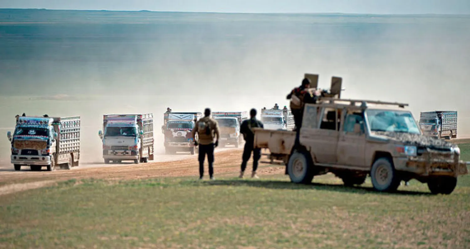 عناصر «سوريا الديمقراطية» يحرسون حافلات لمدنيين هربوا من المعارك مع {داعش} بدير الزور شرق سوريا (أ.ف.ب)