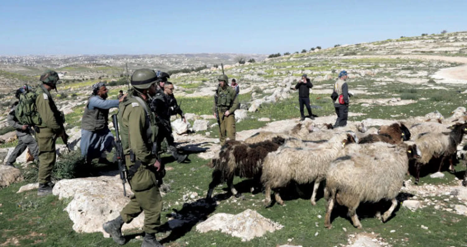 مزارع من بلدة يطا جنوب الخليل يجادل جنوداً إسرائيليين قاموا بتدمير شبكة مياه أول من أمس بحجة عدم حصوله على إذن (إ.ب.أ)