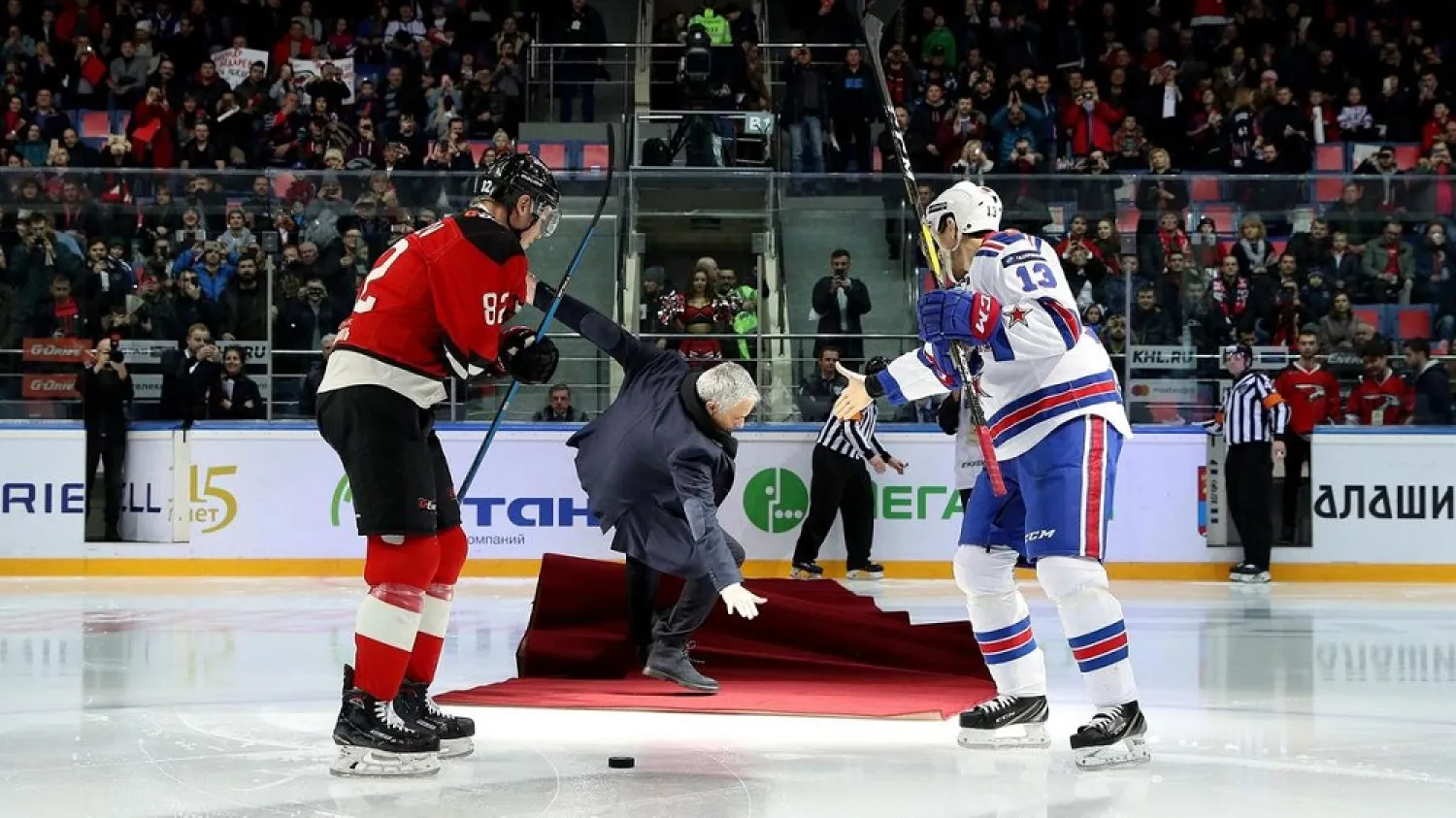 Jose Mourinho, center, falls as he drops the puck to start a Continental hockey league match in Balashikha. (AFP)