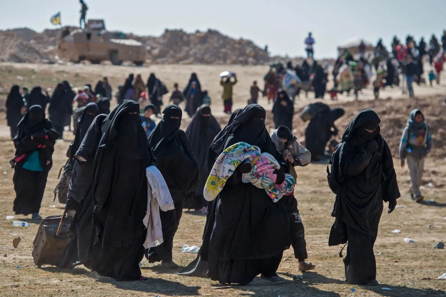 Çocuklarını ve eşyalarını taşıyan kadınlar, Deyr-izor’un doğusunda bulunan DEAŞ’ın son toprağı Baguz kasabasından kaçıyorlar (AFP)