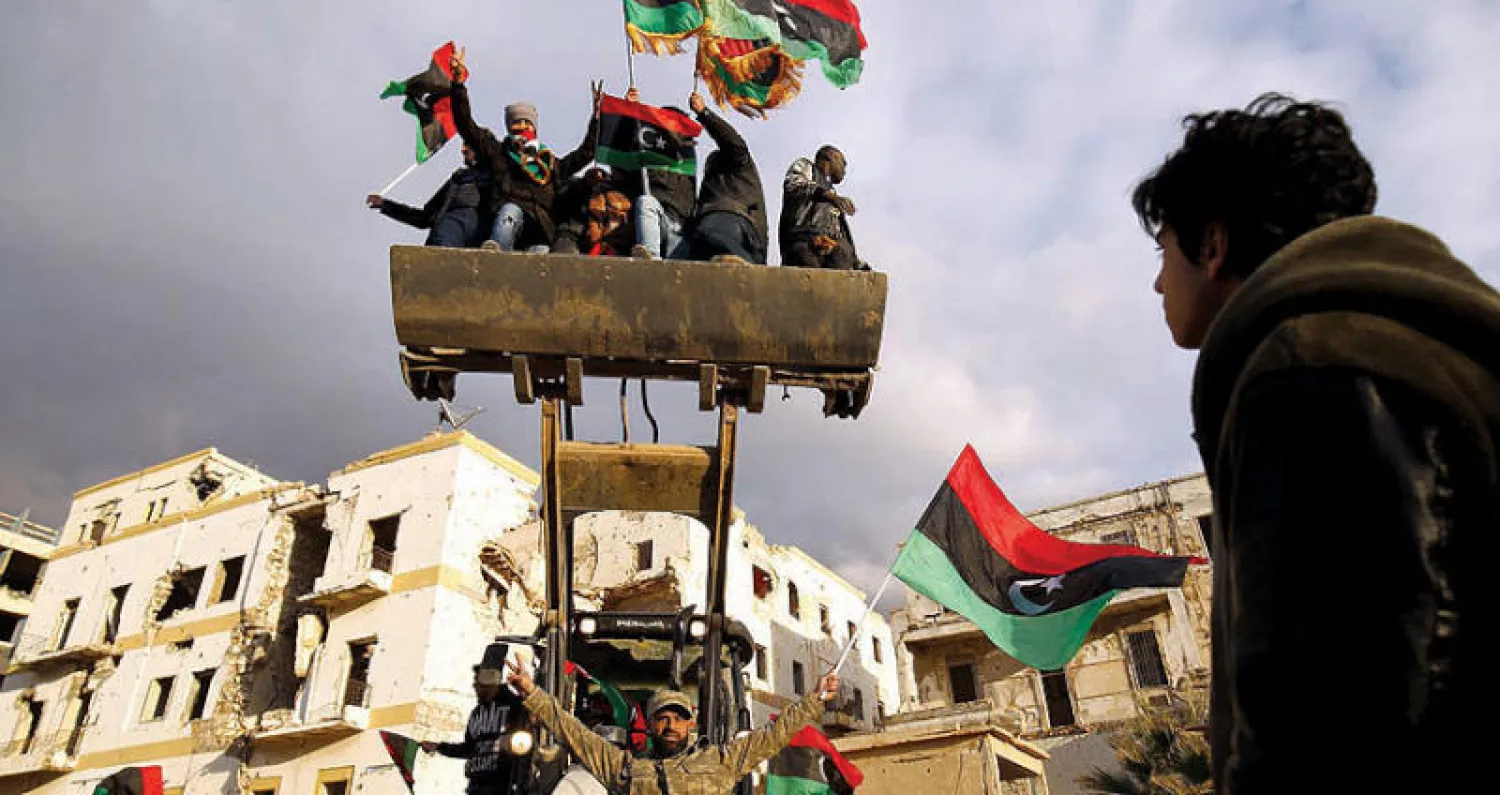 مواطنون يحملون العلم الليبي خلال احتفالهم بذكرى الانتفاضة الليبية وسط بنغازي (أ.ف.ب)