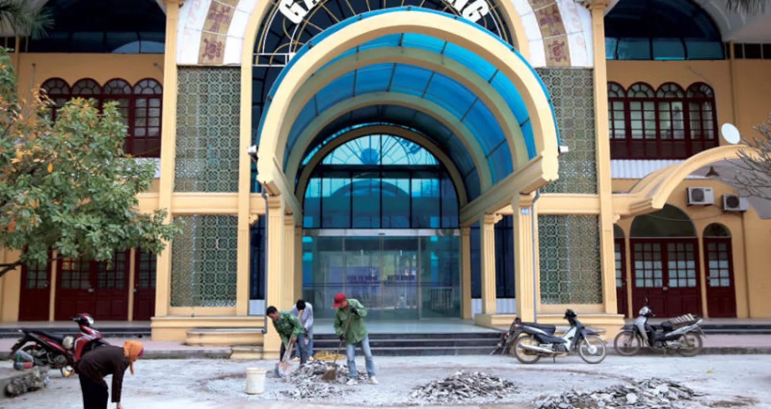 عمال فيتناميون يقومون بإصلاحات عند مدخل محطة قطار دونغ دانغ أمس (إ.ب.أ)