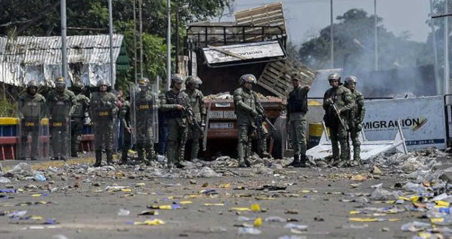 جنود فنزويليون يتفقدون آثار الاشتباكات العنيفة أمس (أ.ف.ب)