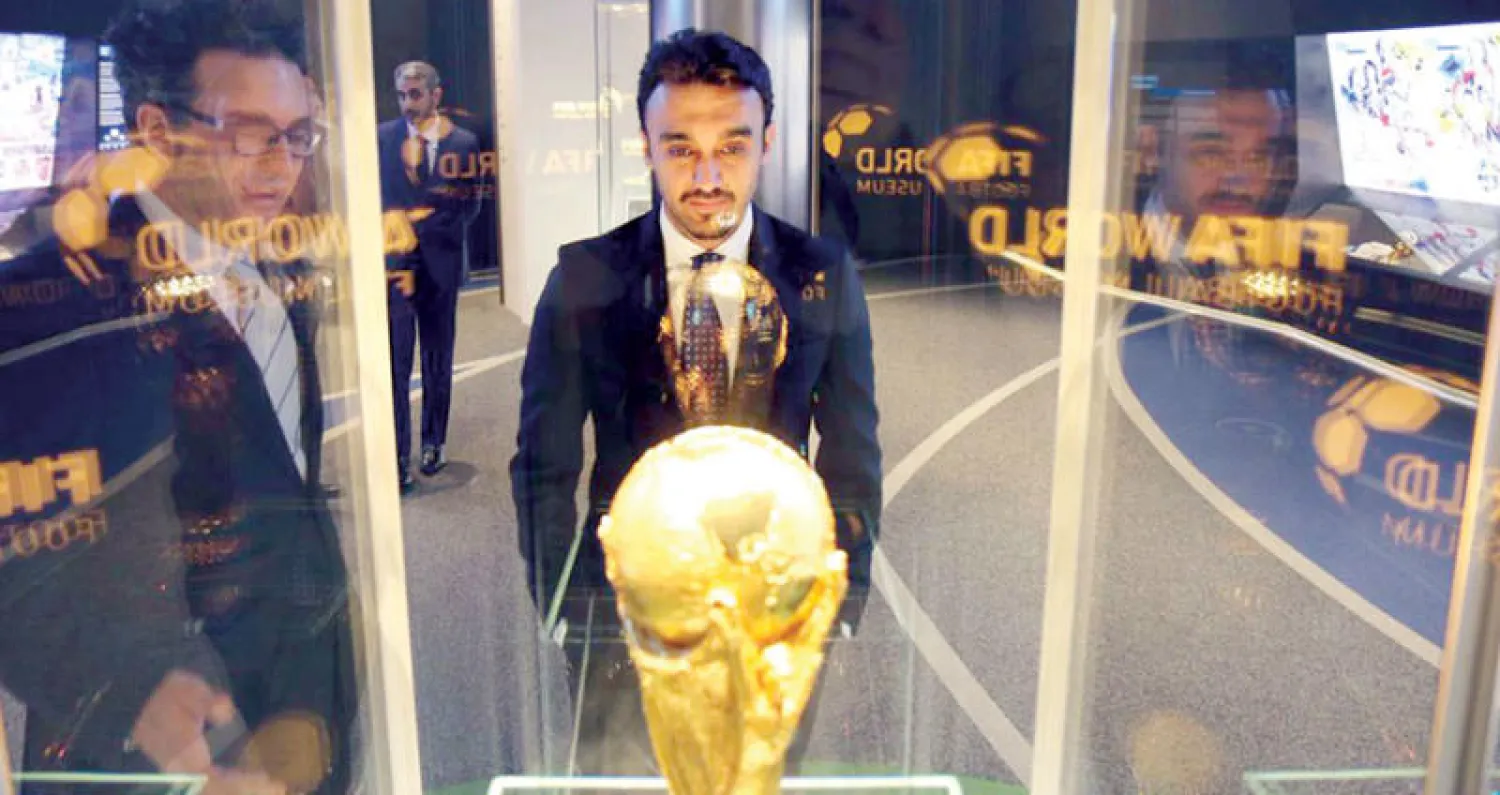 الأمير عبد العزيز الفيصل أمام النسخة الأصلية من كأس العالم لدى زيارته مقر «فيفا» مؤخراً (الشرق الأوسط)