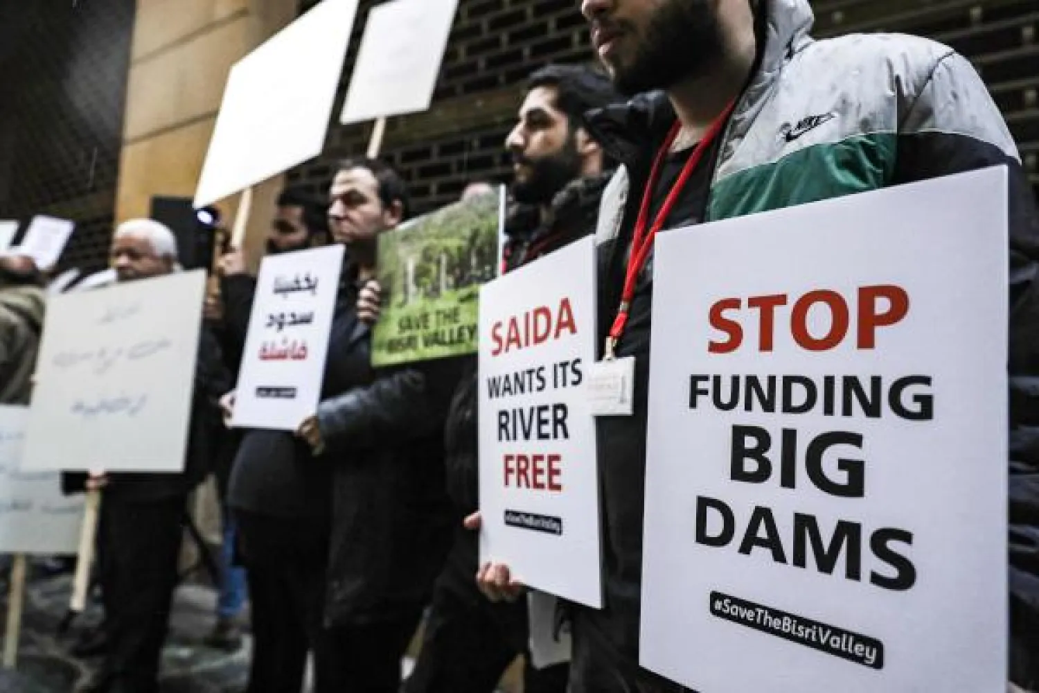 Activists hold signs as they demonstrate in the rain at a sit-in outside the World Bank's headquarters in the center of the Lebanese capital Beirut on March 4, 2019, in protest against the institution's financing of a new dam project in the Bisri valley south of the capital. (Photo by JOSEPH EID / AFP)