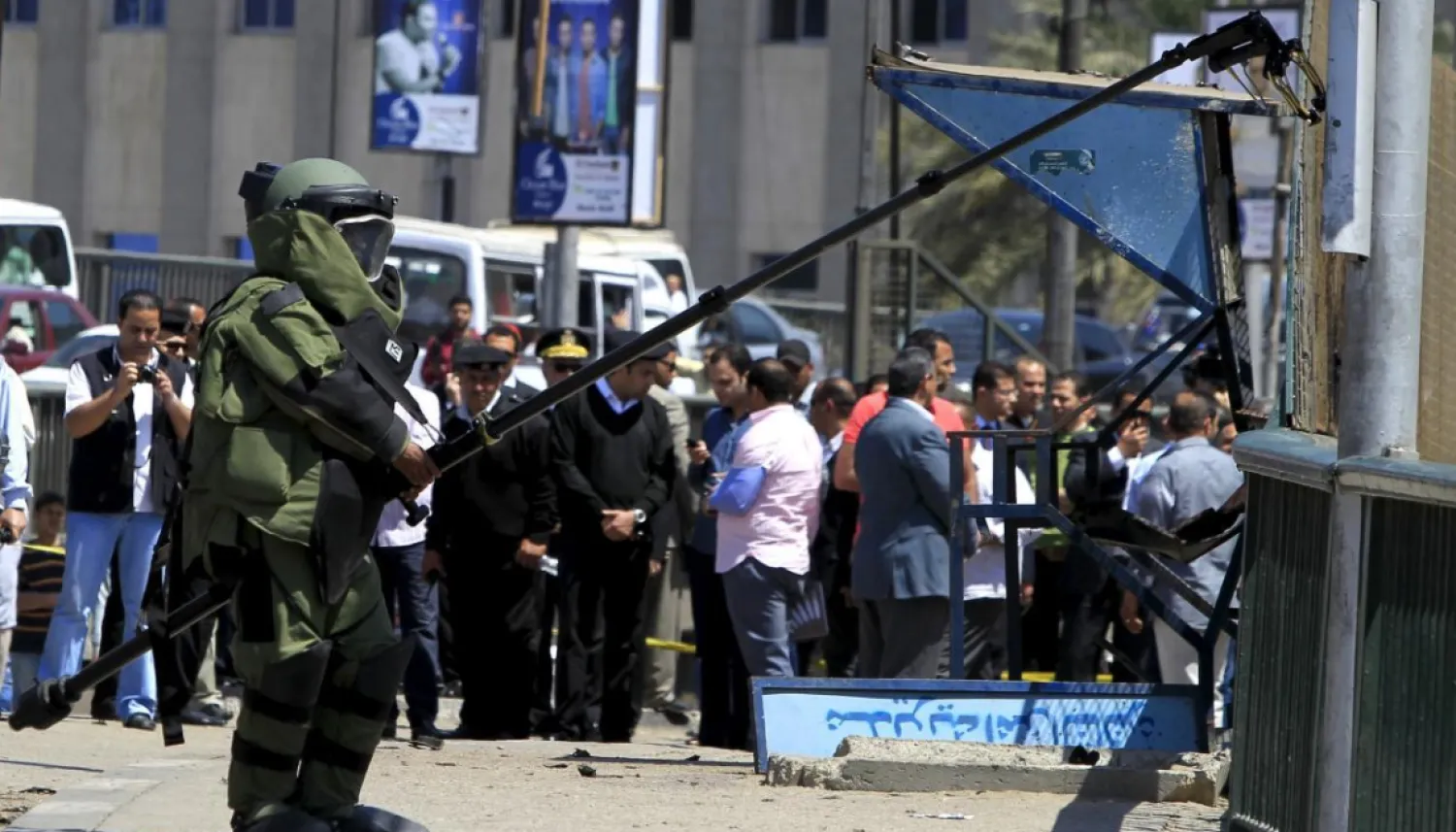 A bomb detonation expert in his suit, accompanied by security personnel (obscured), checks the area after a bomb exploded on a bridge in the Cairo district of Zamalek, April 5, 2015. REUTERS/Mohamed Abd El Ghany