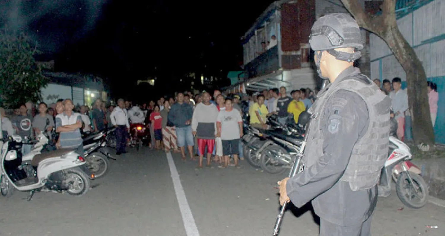 رجل شرطة يبعد مواطنين عن منزل شهد تفجيراً انتحارياً في سيبولجا بإقليم سومطرة الإندونيسي أمس (أ.ف.ب)