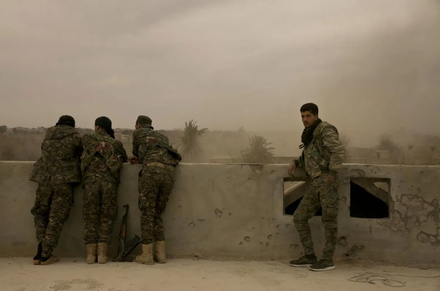 US-backed Syrian Democratic Forces (SDF) soldiers watch from a rooftop the battle to oust ISIS militants from Baghouz, Syria, Wednesday, March 13, 2019. (AP Photo/Maya Alleruzzo)