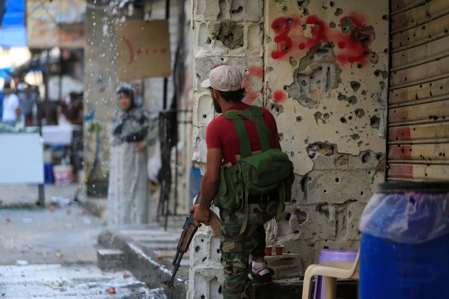 A member of the joint Palestinian security force stands in front of a bullet-riddled wall inside the Ain el-Hilweh refugee camp in southern Lebanon. (Reuters)