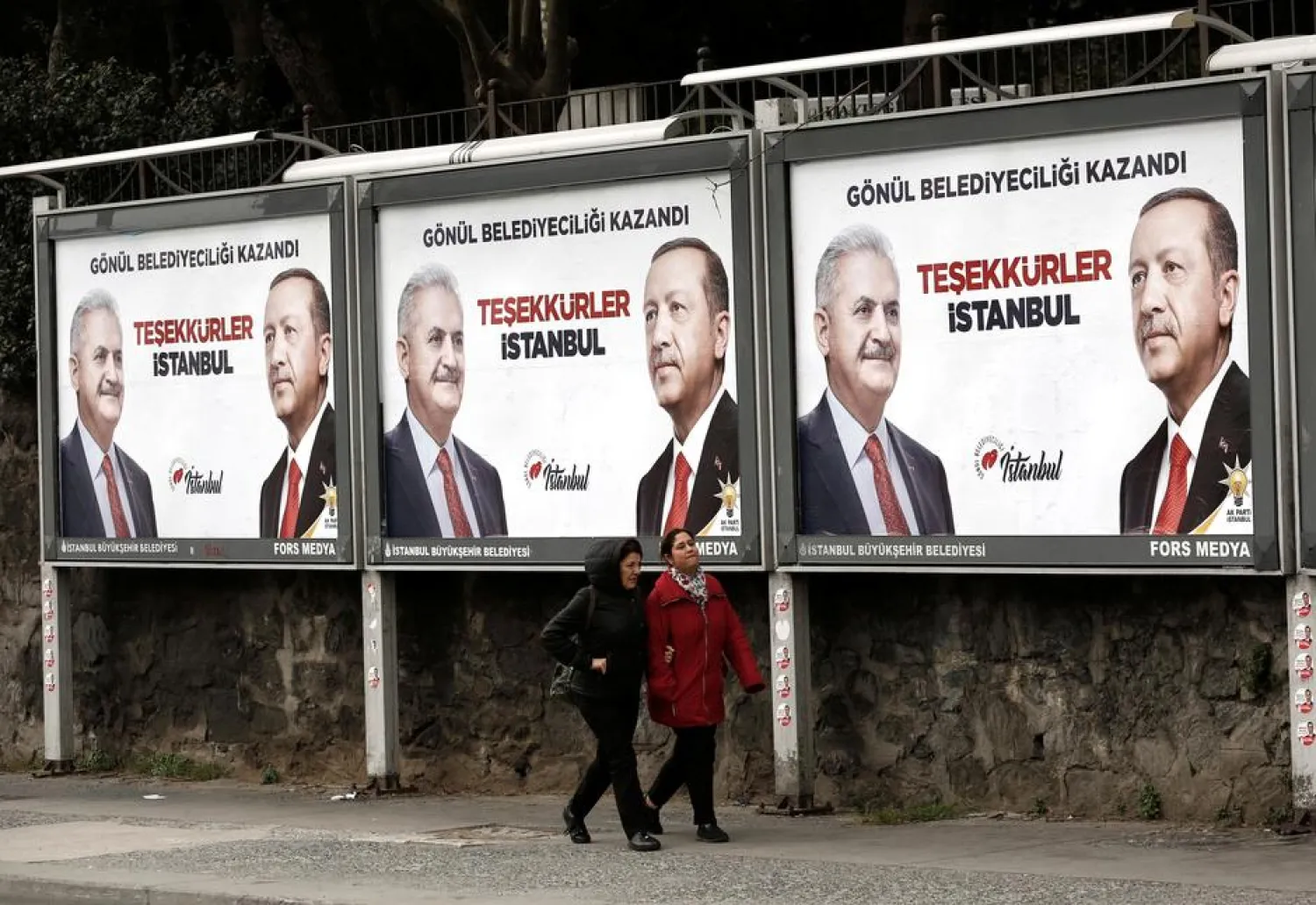 People walk past by AK Party billboards with pictures of Turkish President Erdogan and mayoral candidate Yildirim in Istanbul, Turkey, April 1, 2019. (Reuters)
