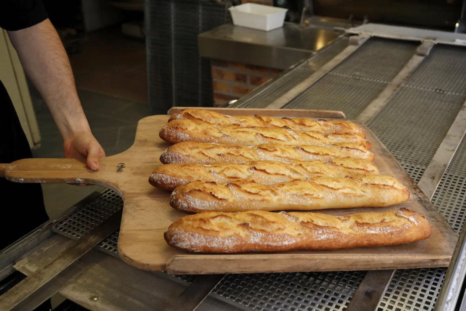 A French baker removes freshly-baked baguettes from the oven in a boulangerie in Paris September 27, 2018. Reuters