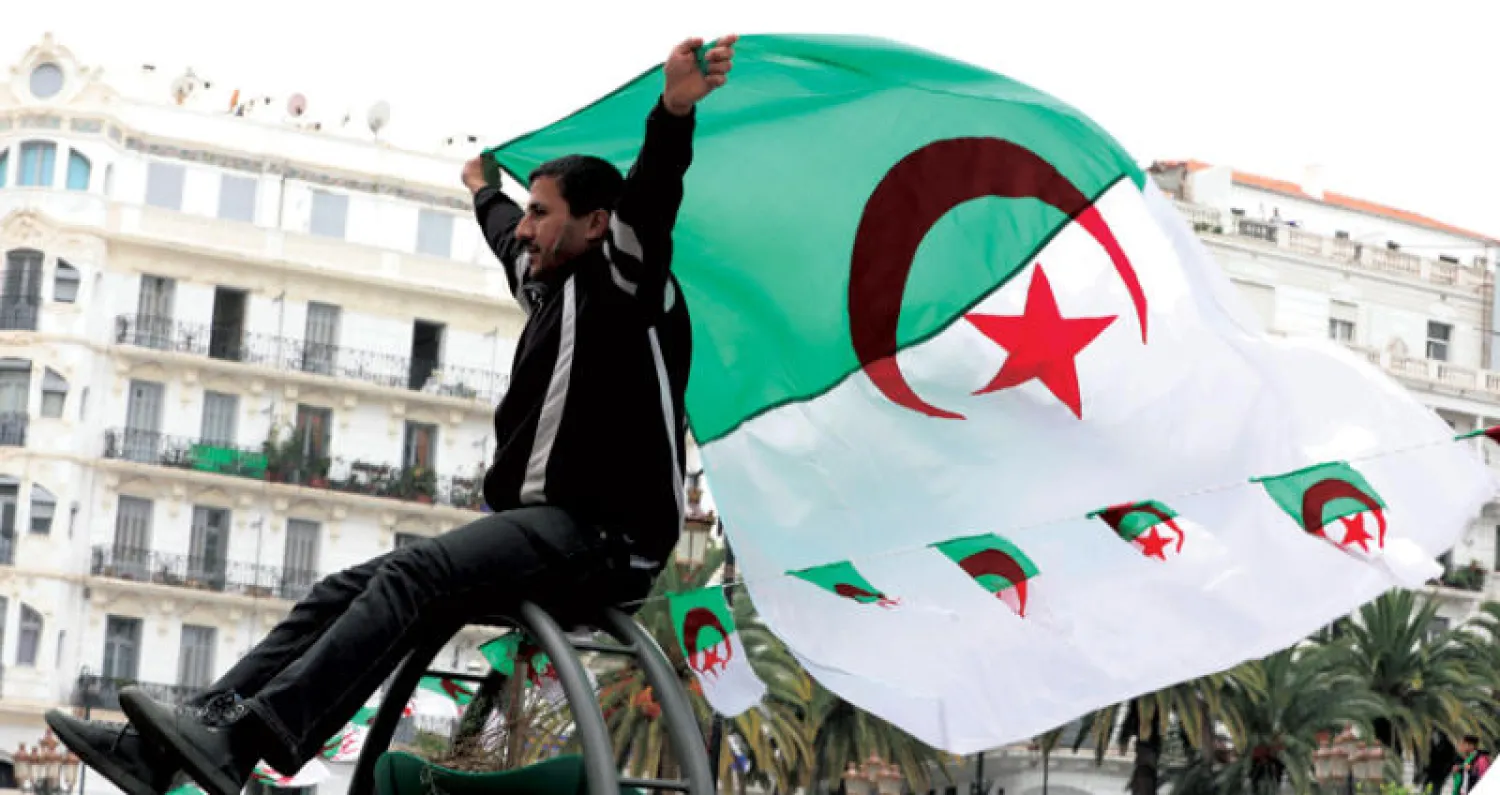 جزائري يحمل علم بلاده خلال المظاهرات التي شهدها وسط العاصمة أمس (إ.ب.أ)