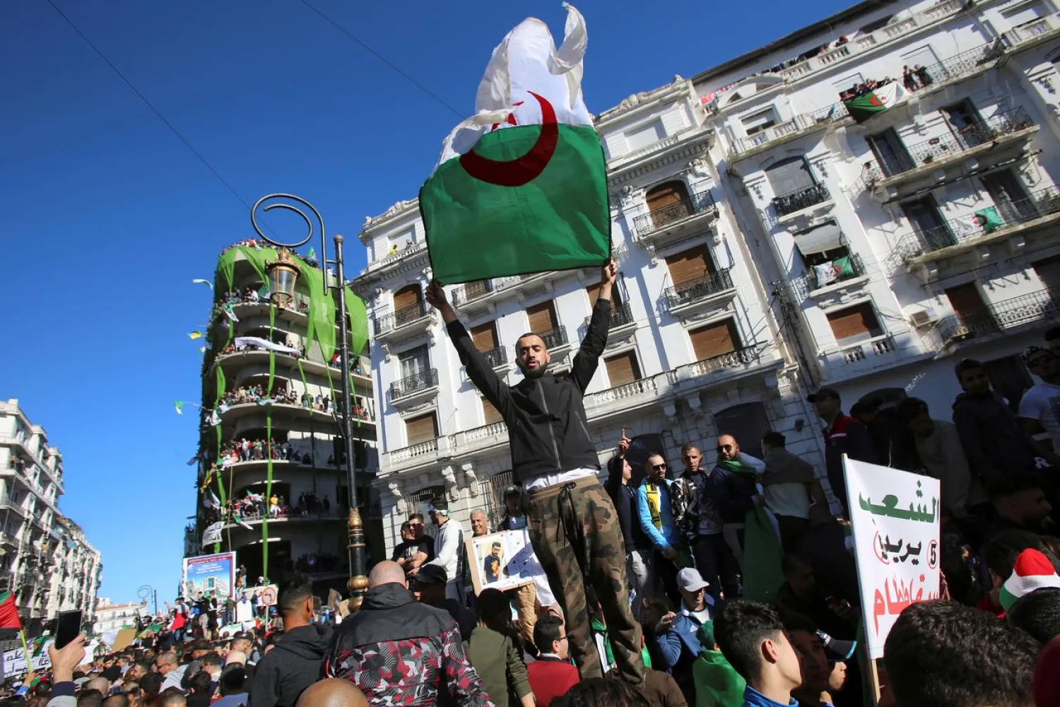 A demonstrator carries a national flag during protests in Algiers, Algeria. (Reuters)