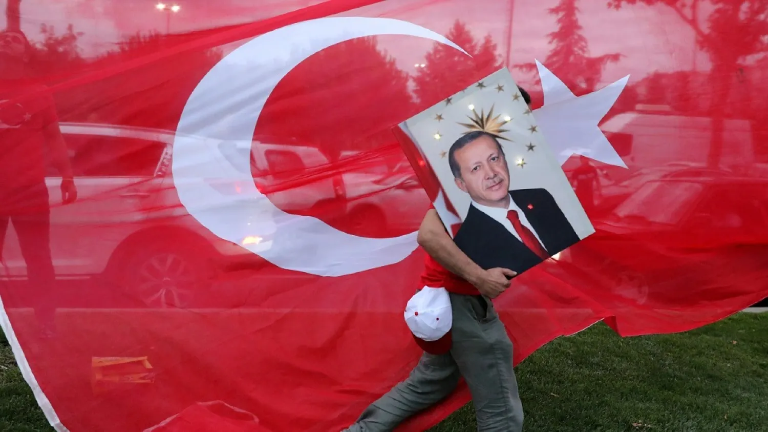 A supporter of President Erdogan holds his picture in front of a Turkish flag, in front of the ruling AK Party headquarters in Istanbul, June 24, 2018. (Reuters)