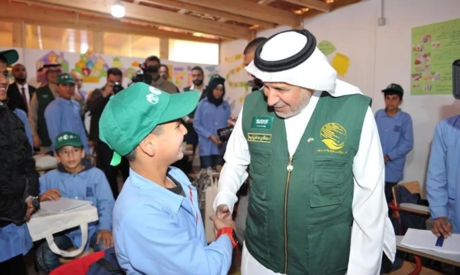 الدكتور عبد الله الربيعة يصافح طالب بمدارس اليونسكو المتوسطة لتعليم اللاجئيين السوريين في لبنان (واس)