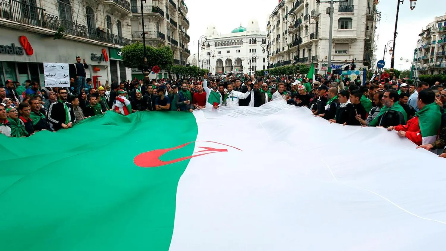 Algerians wave a giant national flag during an anti-government demonstration in the capital Algiers. (AFP)