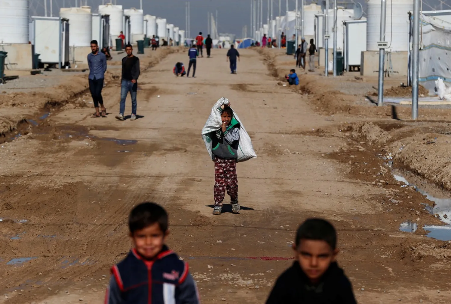 Displaced Iraqi children, who fled ISIS in Mosul, carry their belongings at Khazer camp, Iraq December 10, 2016. (Reuters)