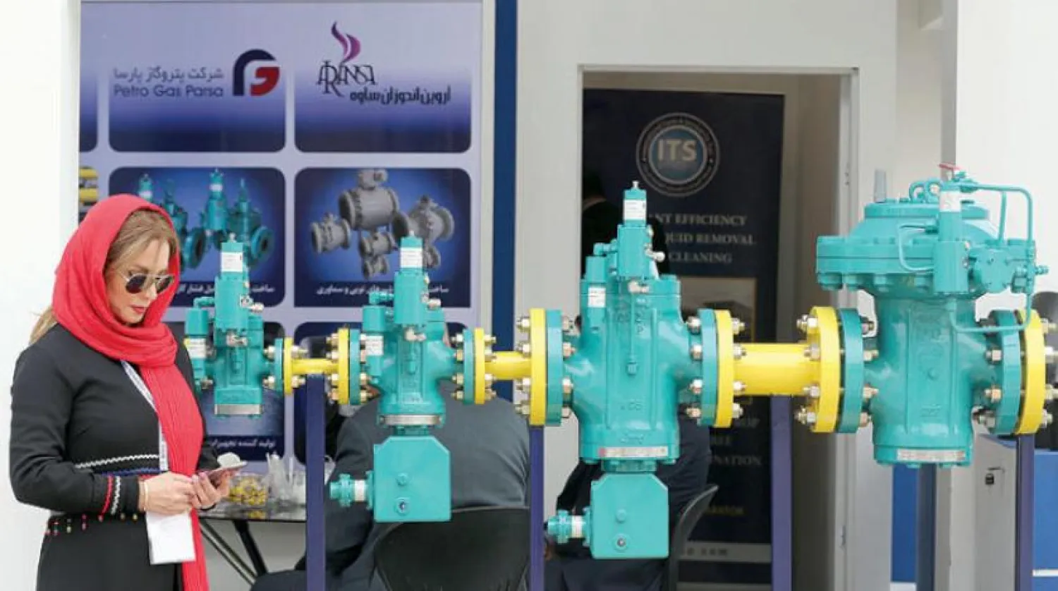 An Iranian employee looks at her phone during the the 24th International Oil, Gas, Petrochemical International Exhibition in Tehran, Iran, 01 May 2019. EPA/ABEDIN TAHERKENAREH