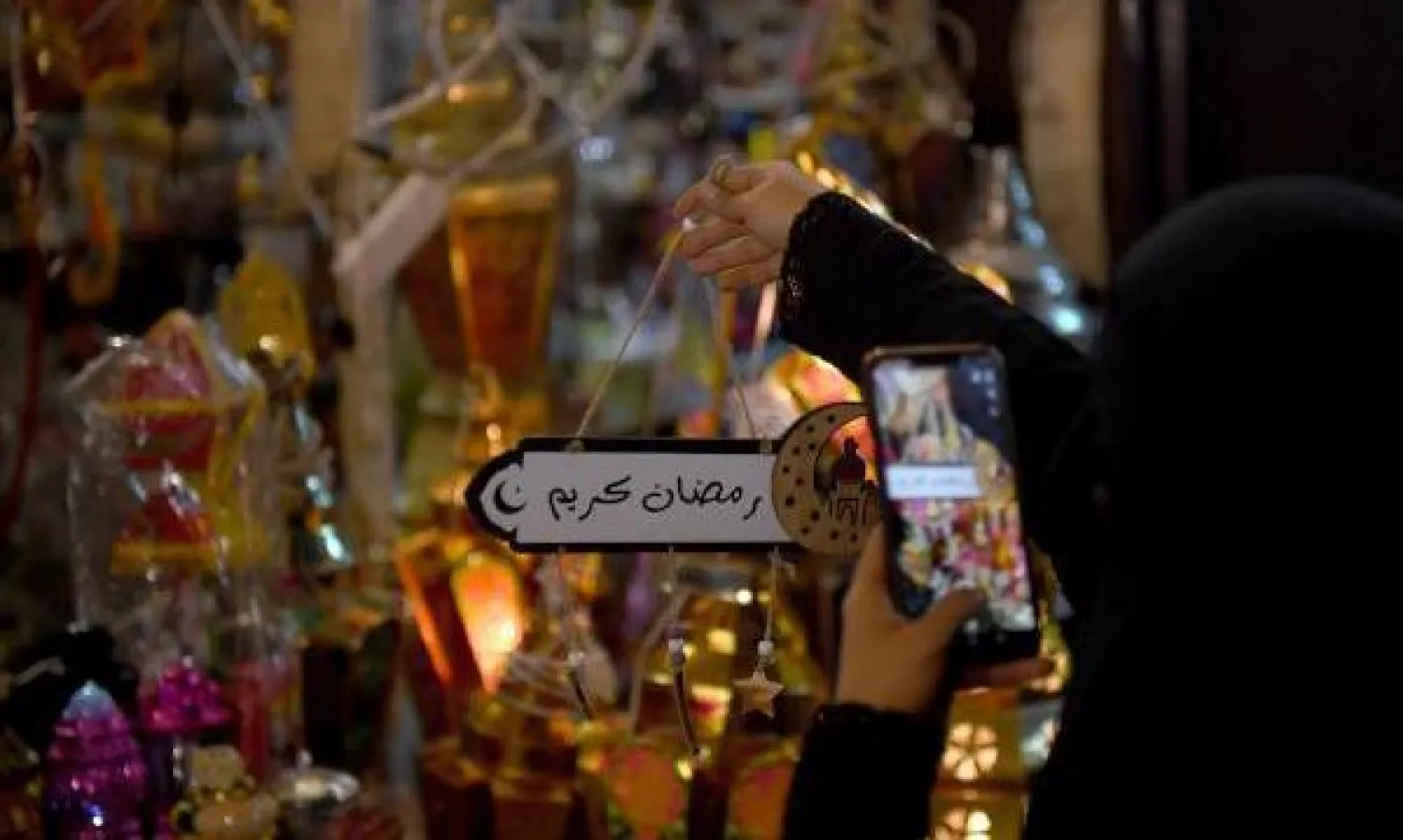 امرأة سعودية تلتقط صورة لزينة تضمنت عبارة «رمضان كريم» (أ.ف.ب)