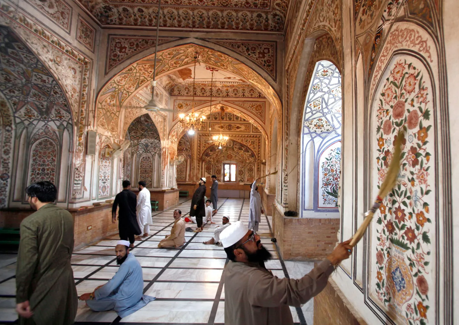 باكستاني ينظف حائط أحد المساجد قبل الشهر الكريم (أ.ب)