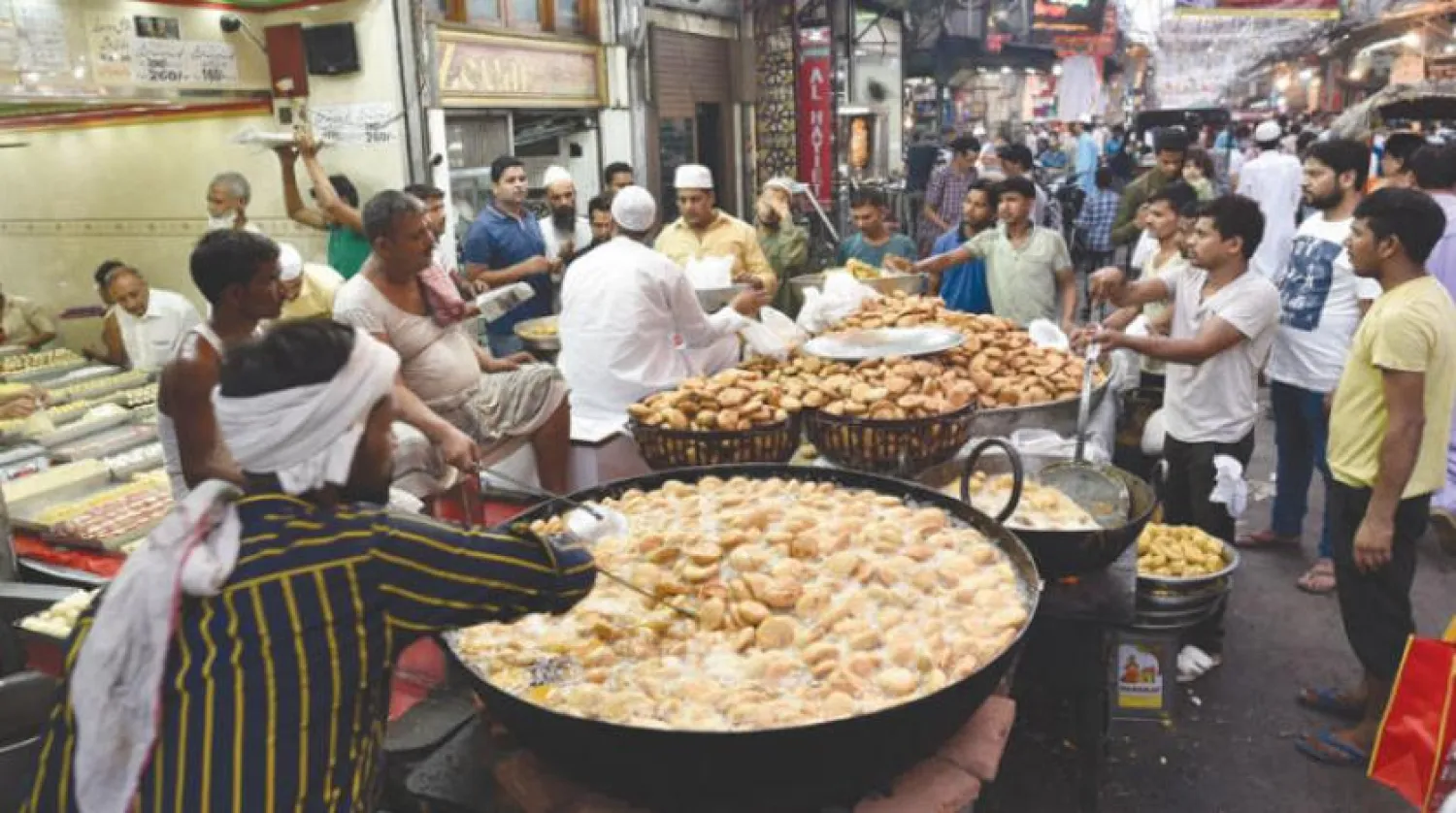 Hindistanlı Müslümanlar Yeni Delhi’deki meşhur dükkanlardan birinden geleneksel Ramazan tatlıları satın alırken (Getty)