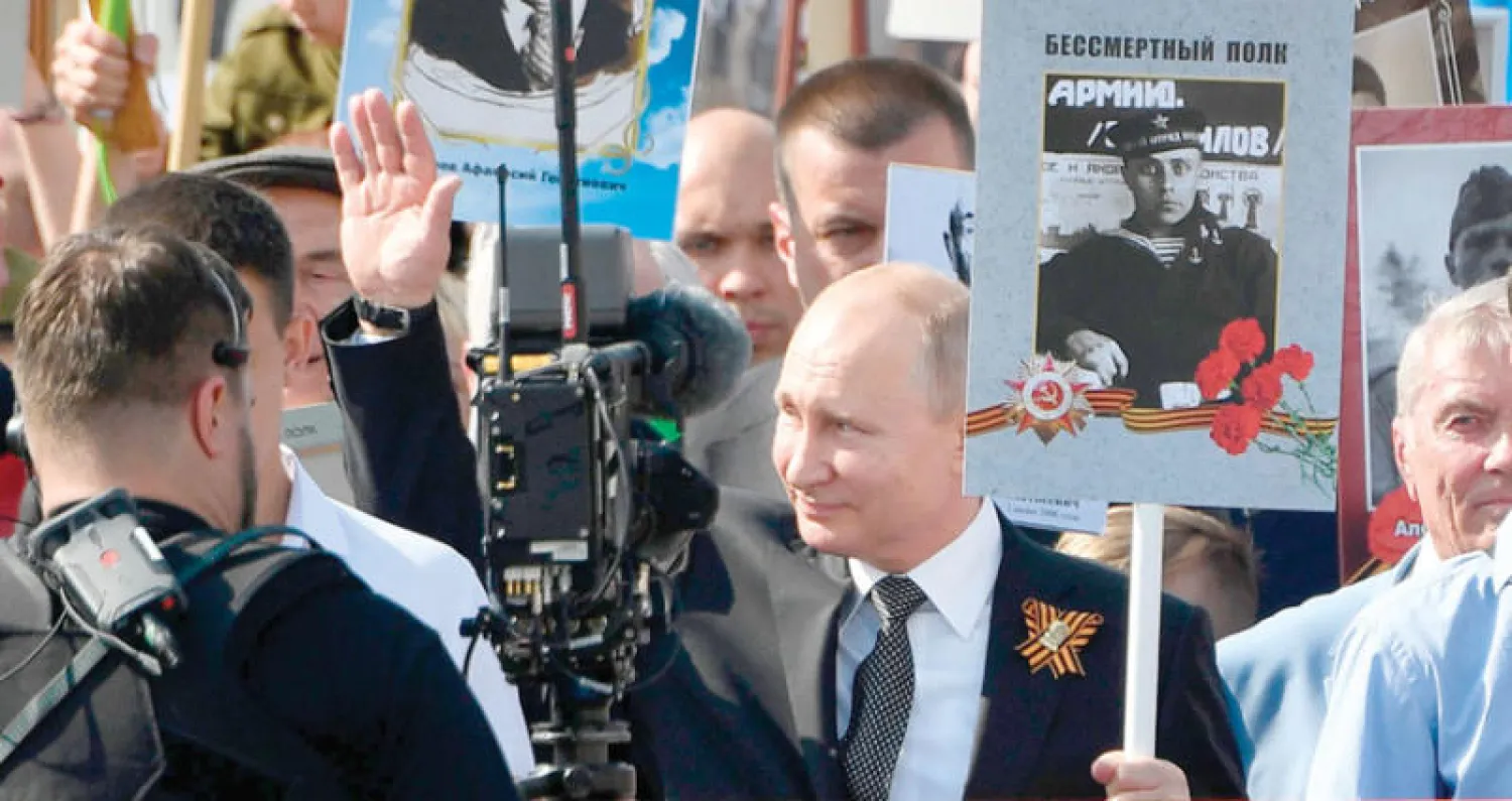 بوتين يحمل صورة والده الذي شارك في الحرب العالمية الثانية في ذكرى عيد النصر على النازية بموسكو أمس (أ.ف.ب)