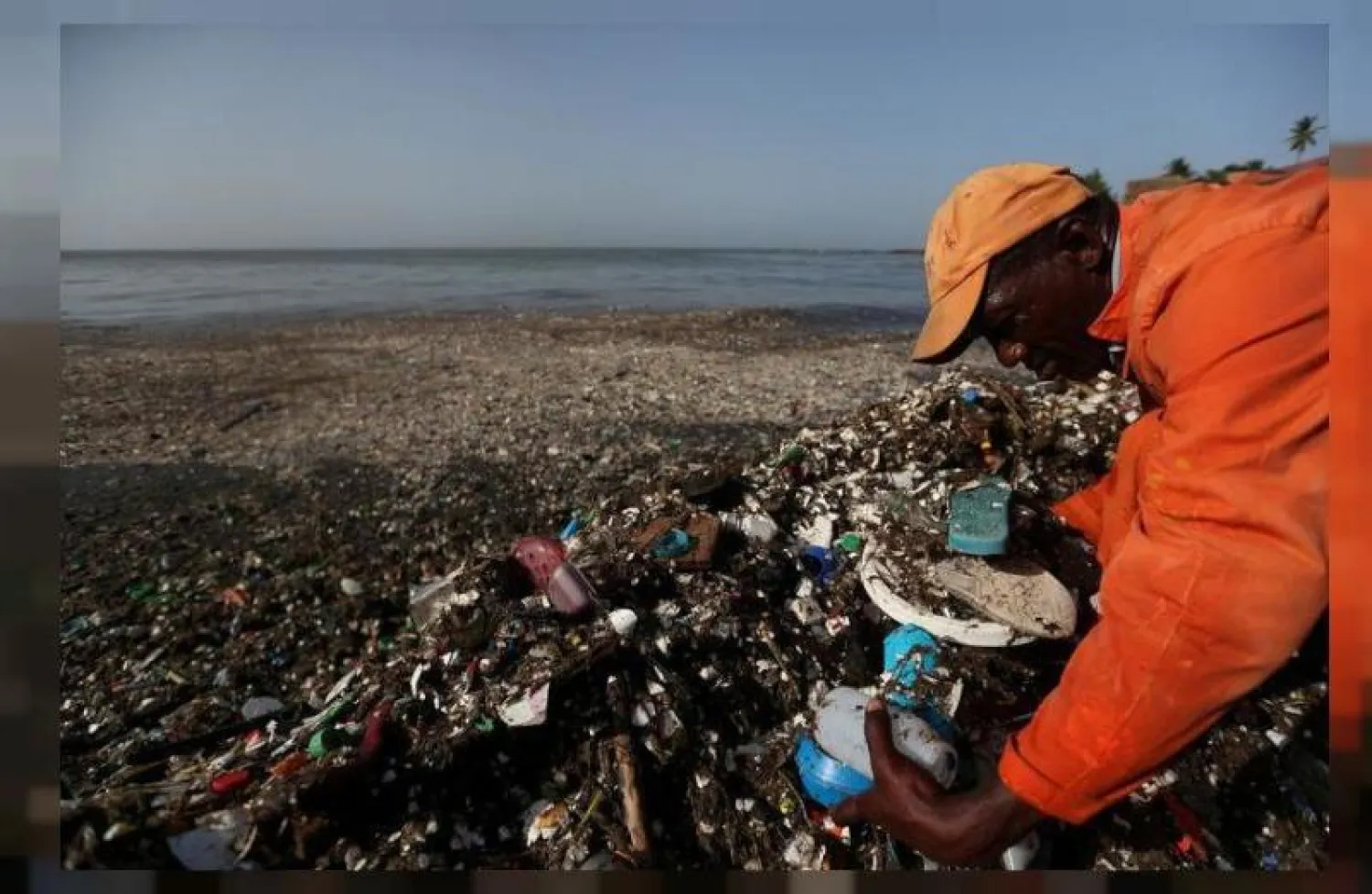 عامل يجمع البلاستيك ومخلفات أخرى على شاطئ في سانتو دومينغو بجمهورية الدومينيكان (أرشيف - رويترز)