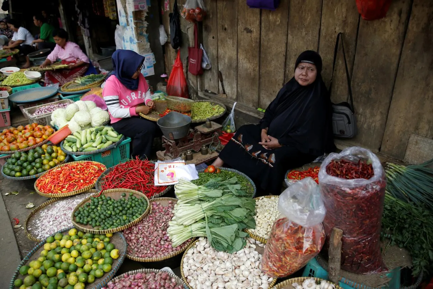 FILE PHOTO: A vegetable seller sits while waiting for customers at the morning market in Jakarta, Indonesia, August 1, 2017. REUTERS/Beawiharta