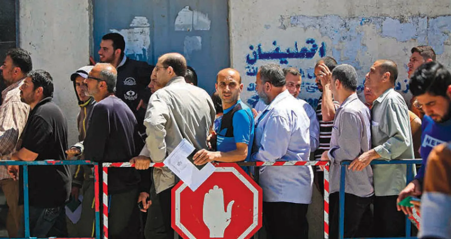 فلسطينيون يقفون في طابور في انتظار الحصول على مساعدات مالية في مدينة غزة أمس (أ.ف.ب)