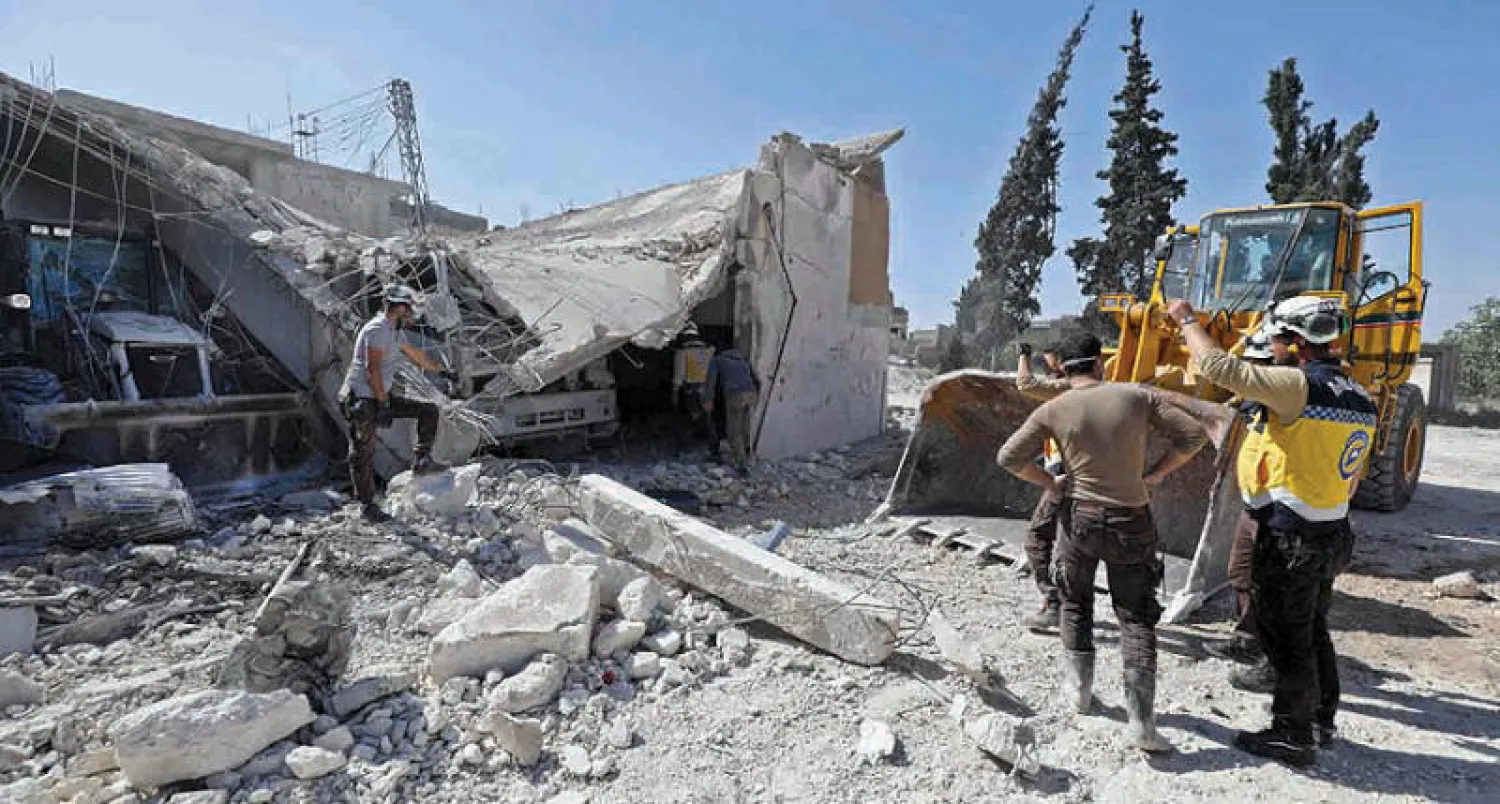 عناصر من الدفاع المدني يتفقدون آثار الدمار في كفرنبل في ريف إدلب أمس (أ.ف.ب)