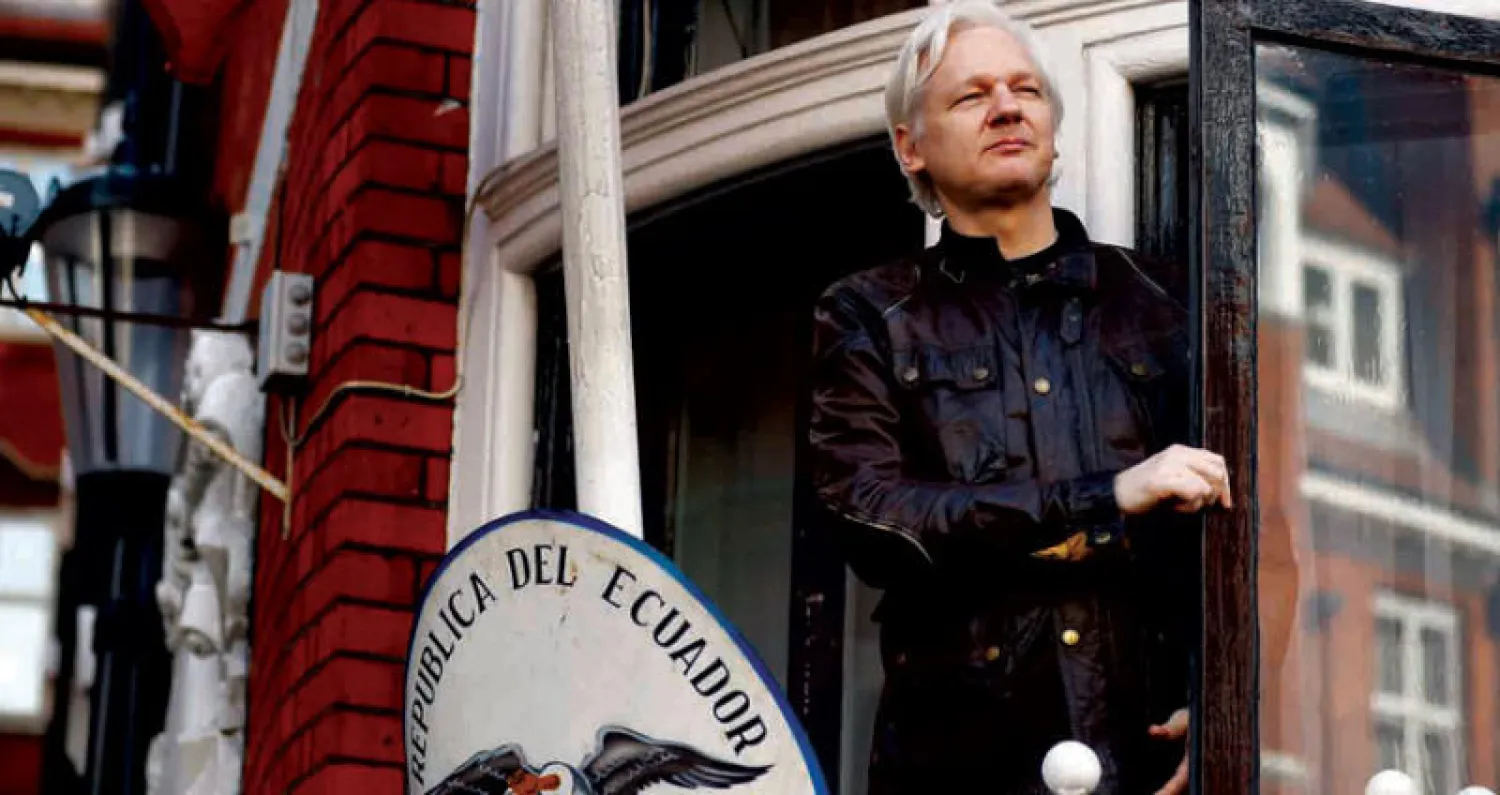 صورة أرشيفية لأسانج وهو يطل من شرفة السفارة الإكوادورية لدى بريطانيا في مايو 2017 (أ.ب)