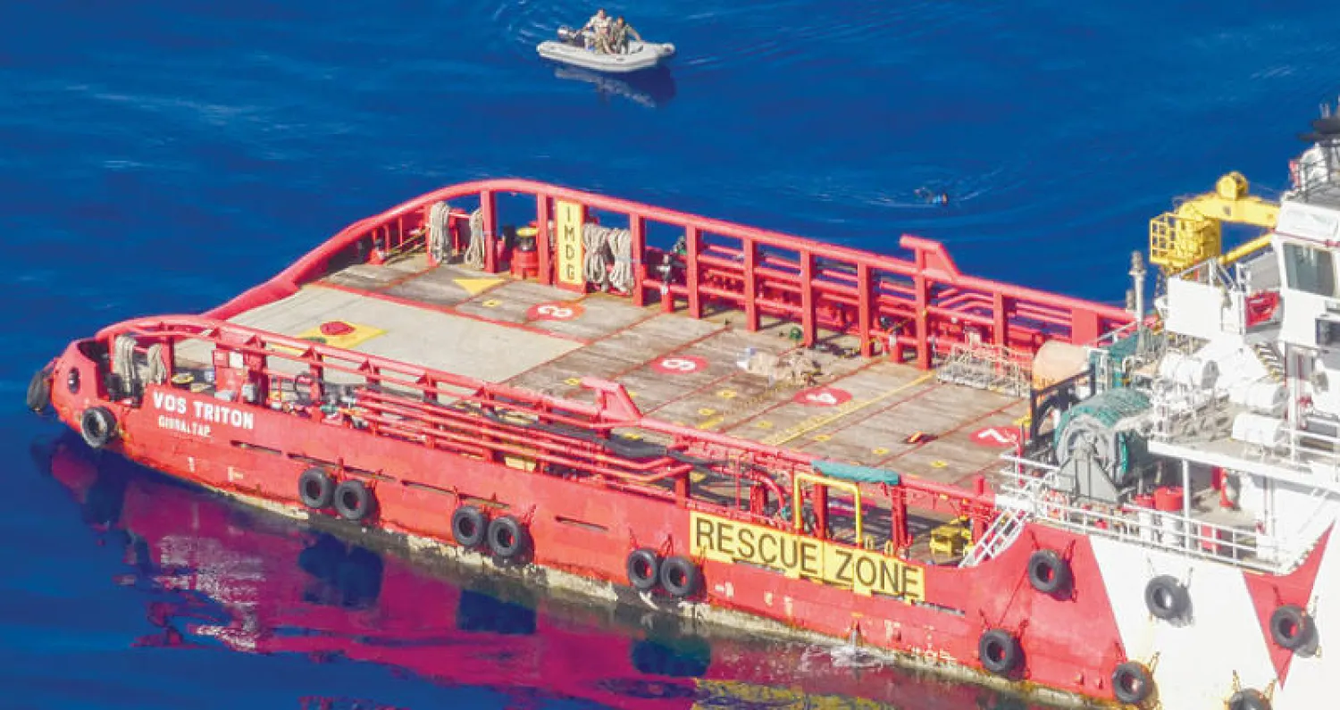 زورق لخفر السواحل يقترب من سفينة تجارية على متنها مهاجرون أمام السواحل الليبية أمس (رويترز)