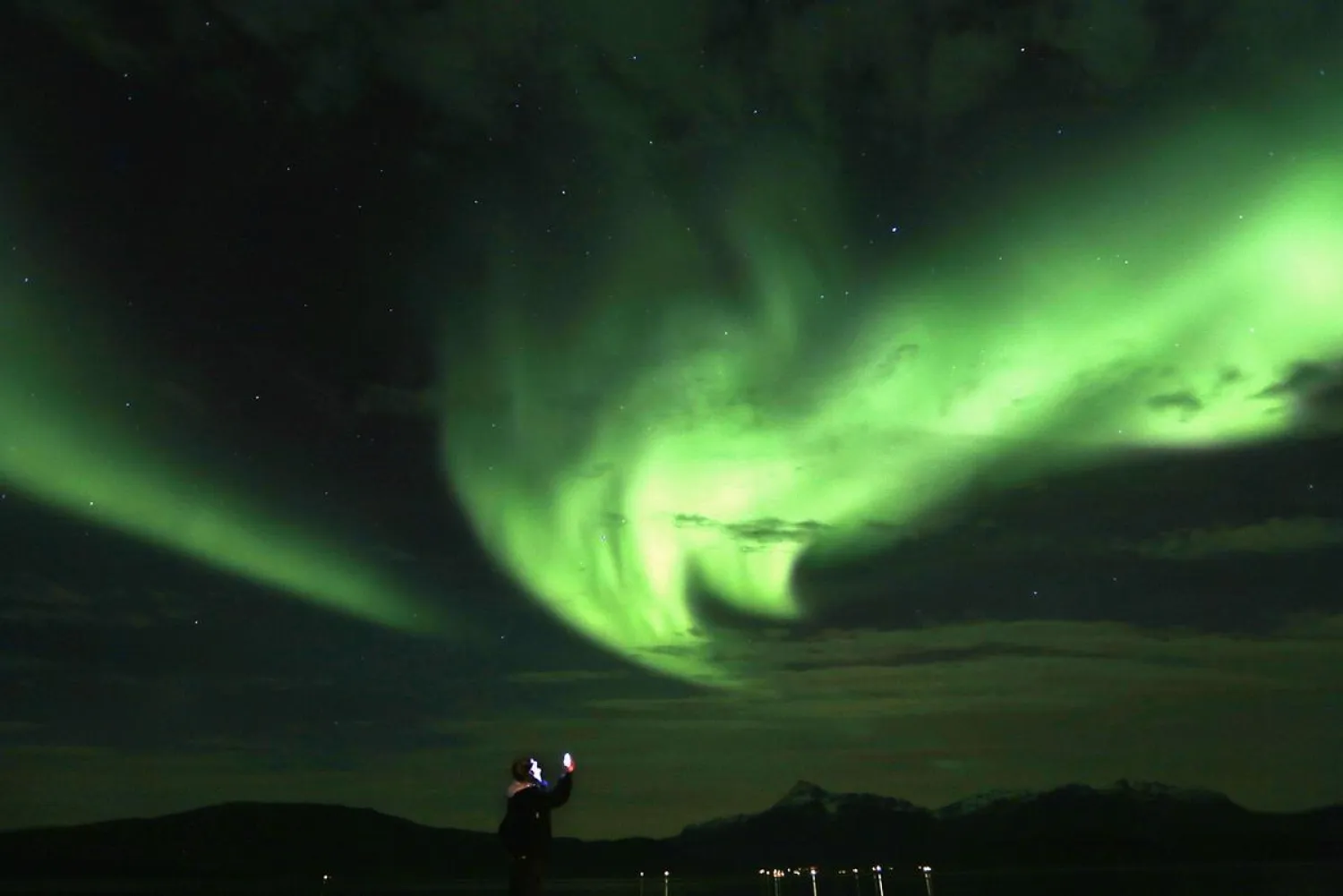 A tourist takes photos of an Aurora Borealis (Northern Lights)
over the Bals-Fiord north of the Arctic Circle, near the village of
Mestervik, Norway, on September 30, 2014. Reuters/Yannis Behrakis