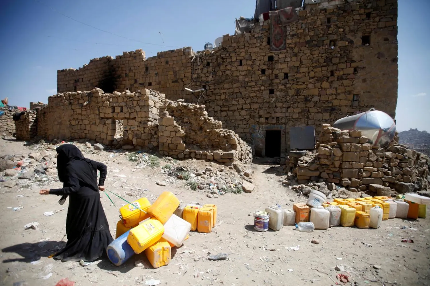 A woman displaced from the Red Sea port city of Hodeidah pulls empty canisters outside her family shelter in Sanaa, Yemen November 2, 2018. REUTERS/Mohamed al-Sayaghi/File Photo