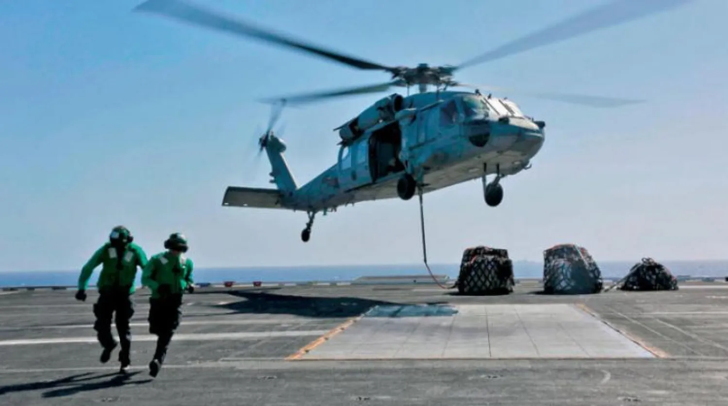 Körfez sularındaki Abraham Lincoln uçak gemisi pistinde yer alan Sea Hawk helikopteri yakınlarındaki iki Amerikalı denizci (AFP)