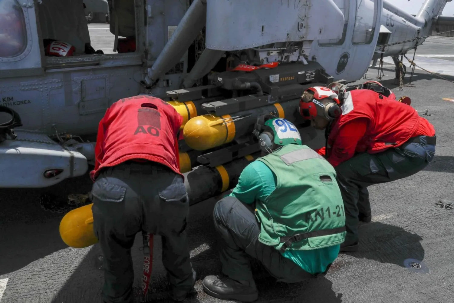 In this Wednesday, May 15, 2019, photo released by the US Navy, Aviation Ordnanceman Airman Tyrik Williams, right, Aviation Electrician's Mate 2nd Class Nathan Hernandez, middle, and Aviation Ordnanceman 2nd Class Kristina Thompson, left, load an AGM-114 Hellfire missile onto an MH-60S Seahawk helicopter on board the USS Abraham Lincoln. (Mass Communication Specialist Seaman Michael Singley, US Navy via AP)