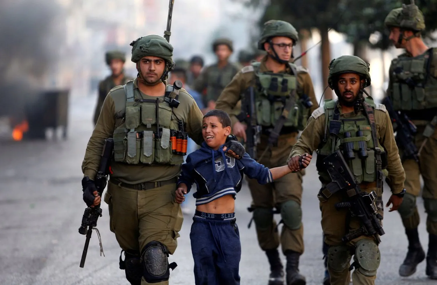 Israeli soldiers detain a Palestinian boy during clashes in West Bank. Credit: Reuters