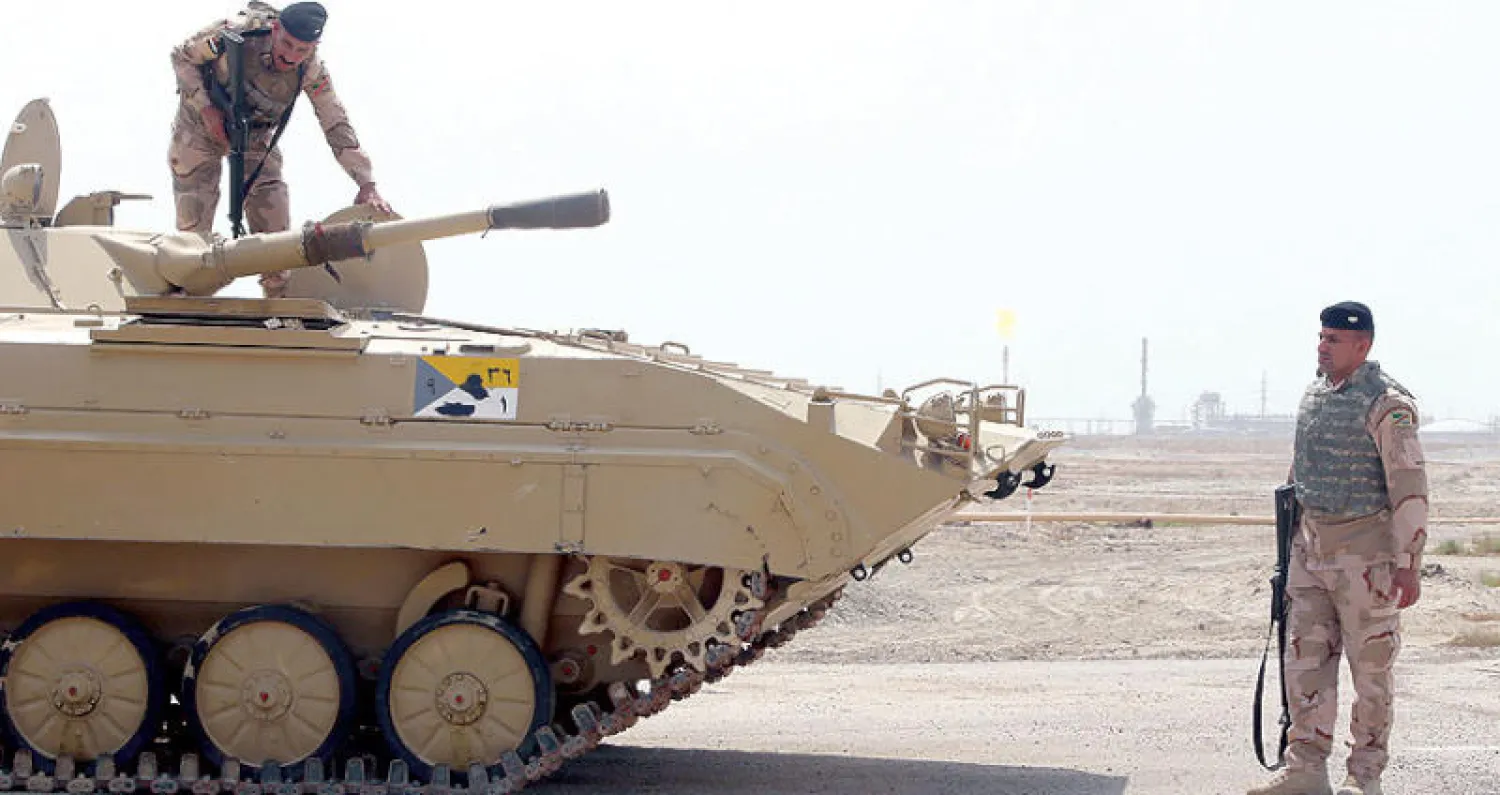 حراسة عسكرية لمدخل حقل «القرنة 1» في محافظة البصرة الذي تعمل فيه شركة «إكسون موبيل» الأميركية (رويترز)