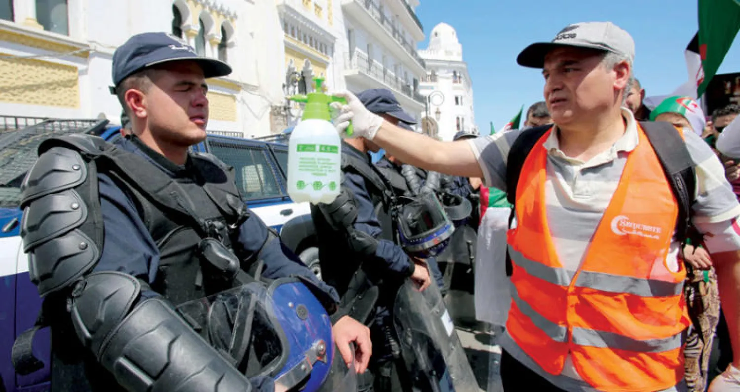 جزائري يرش شرطياً بالماء لتخفيف آثار درجات الحرارة المرتفعة في العاصمة أول من أمس (رويترز)