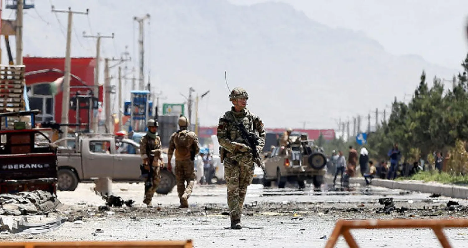 جنود أفغان وآخرون من «الناتو» في موقع التفجير الانتحاري الذي استهدف قافلة أميركية وسط كابل أمس (رويترز)