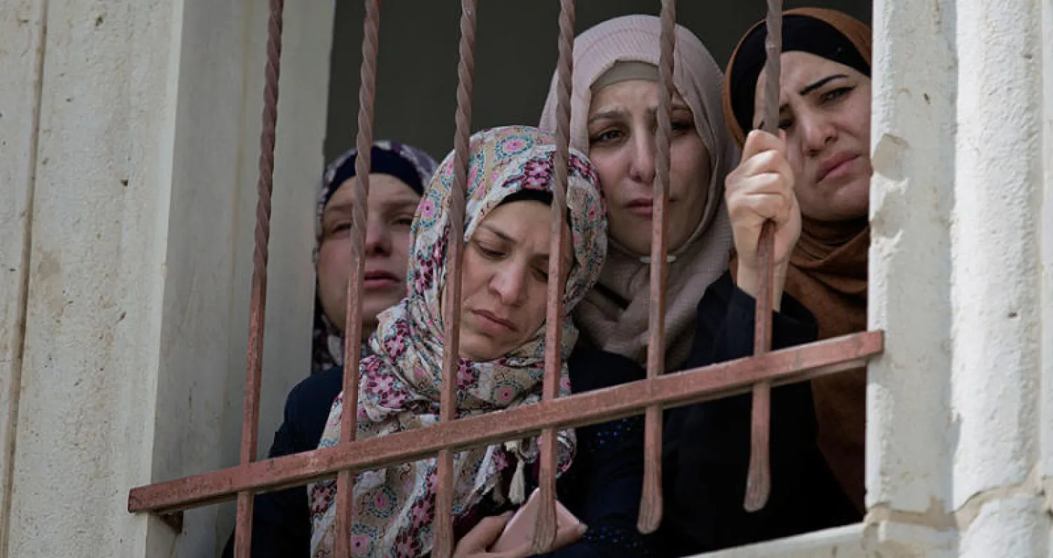 أسرة الفتى القتيل عبد الله غيث  تتابع تشييع جنازته من نافذة منزل الأسرة في الخليل أمس (أ.ب)