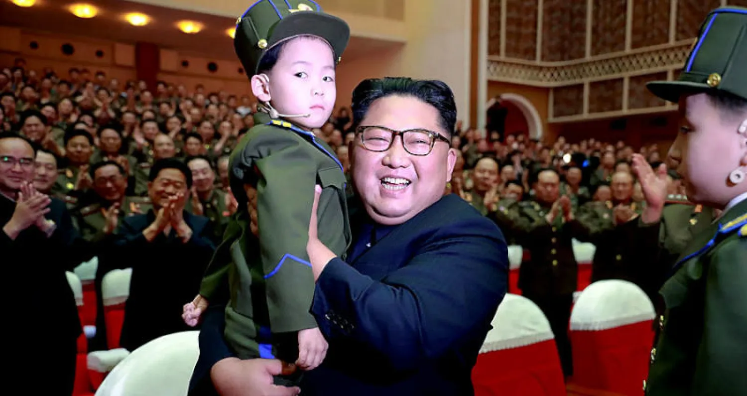 كيم يحمل طفلا خلال حضوره عرضاً فنياً في بيونغ يانغ أمس (أ.ف.ب)