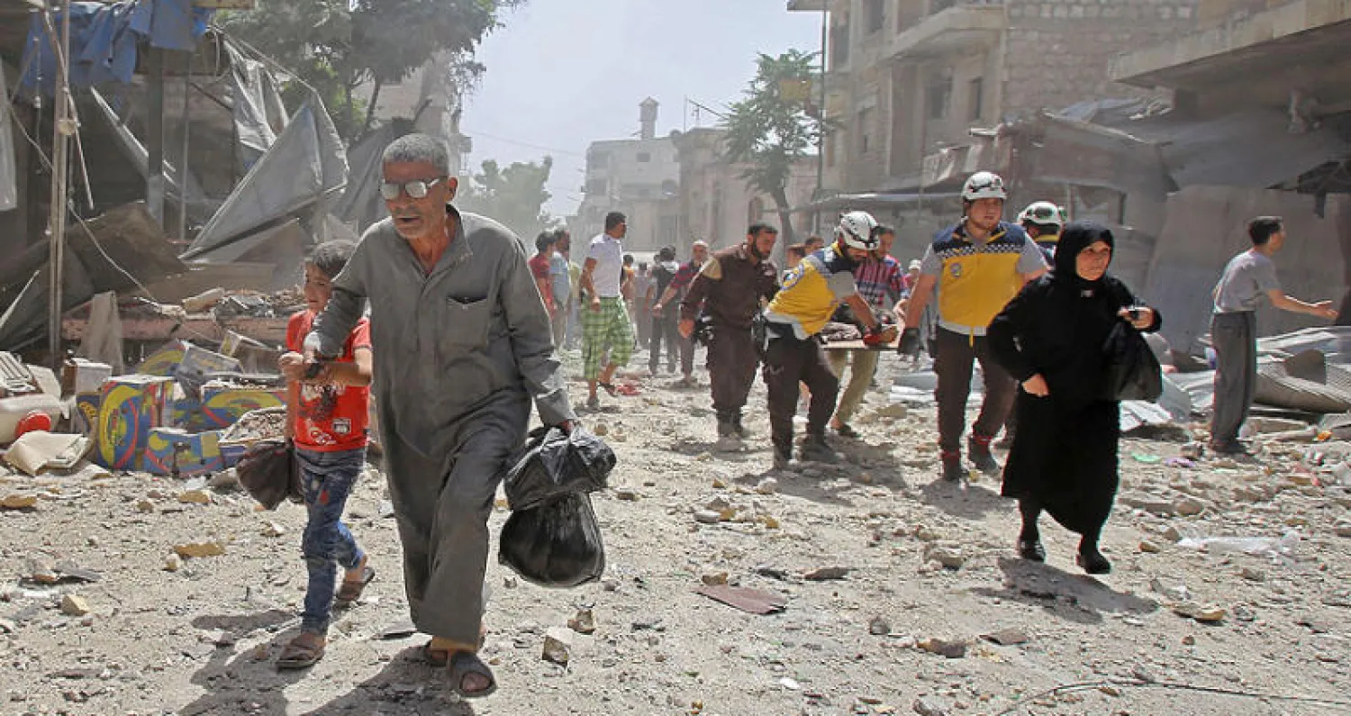 عناصر من «الدفاع المدني» يسعفون شخصاً بعد غارة على معرة النعمان في إدلب أمس (أ.ف.ب)