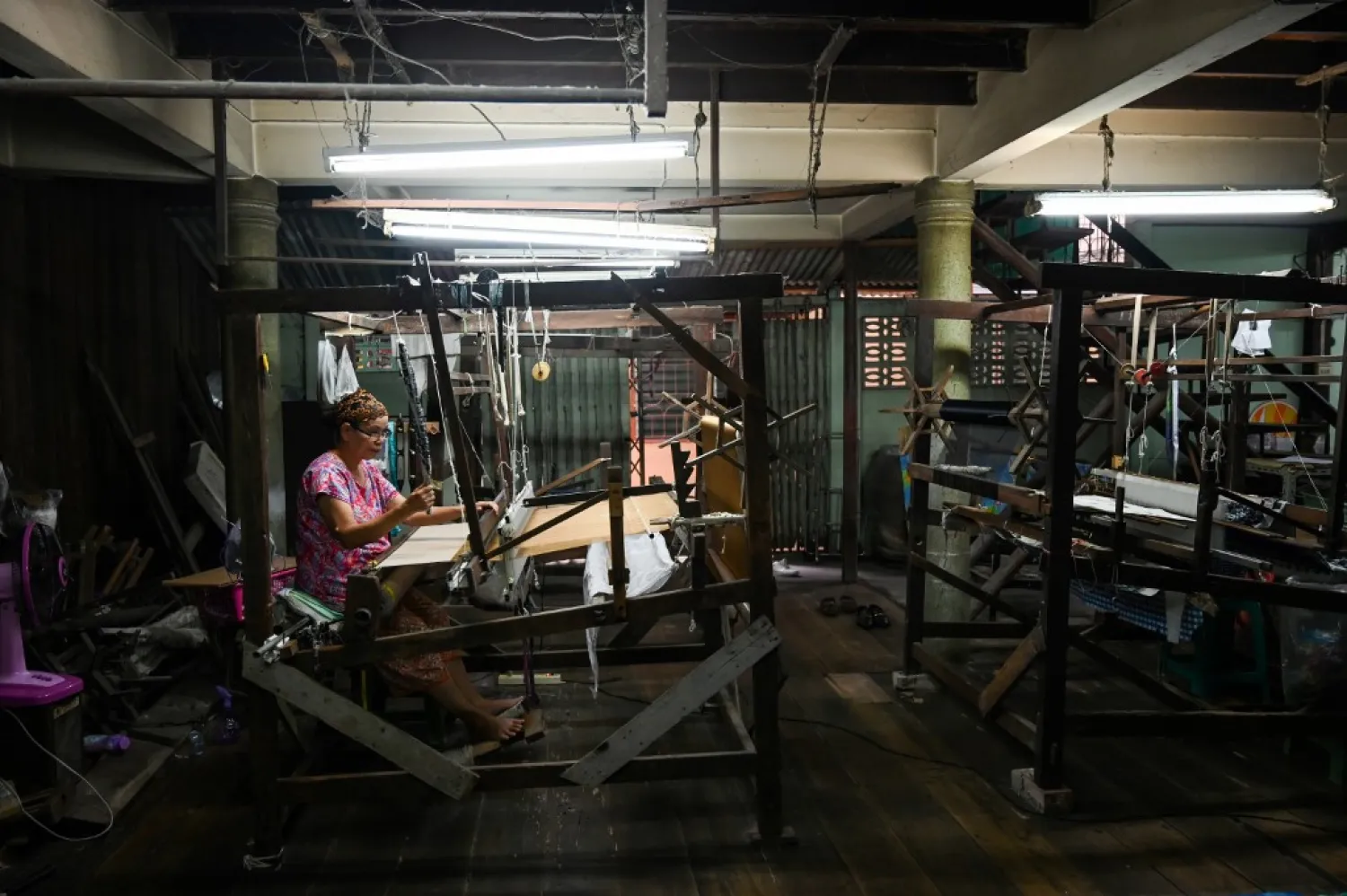 This photo taken on May 22, 2019 shows Rampai Sripetch, a 65-year-old Thai Muslim woman, weaving silk fabric on a loom at a workshop near Darul Falah mosque in Bangkok. (AFP)