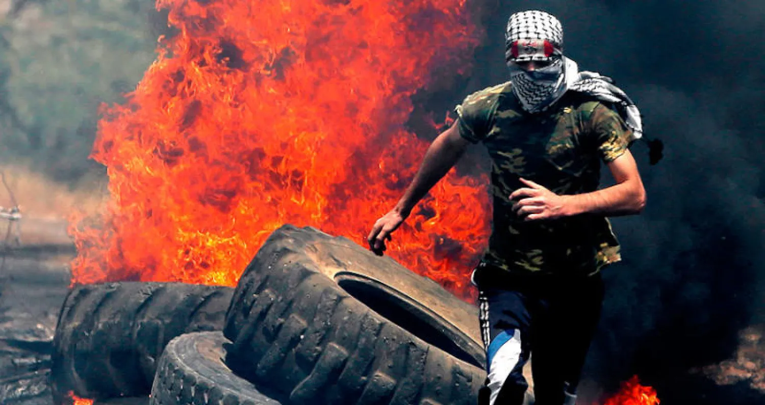 شاب فلسطيني يحاول الاحتماء من جنود إسرائيليين يلاحقونه خلال قمع احتجاجات في كفر قدوم قرب نابلس بالضفة الغربية أمس (أ.ف.ب)