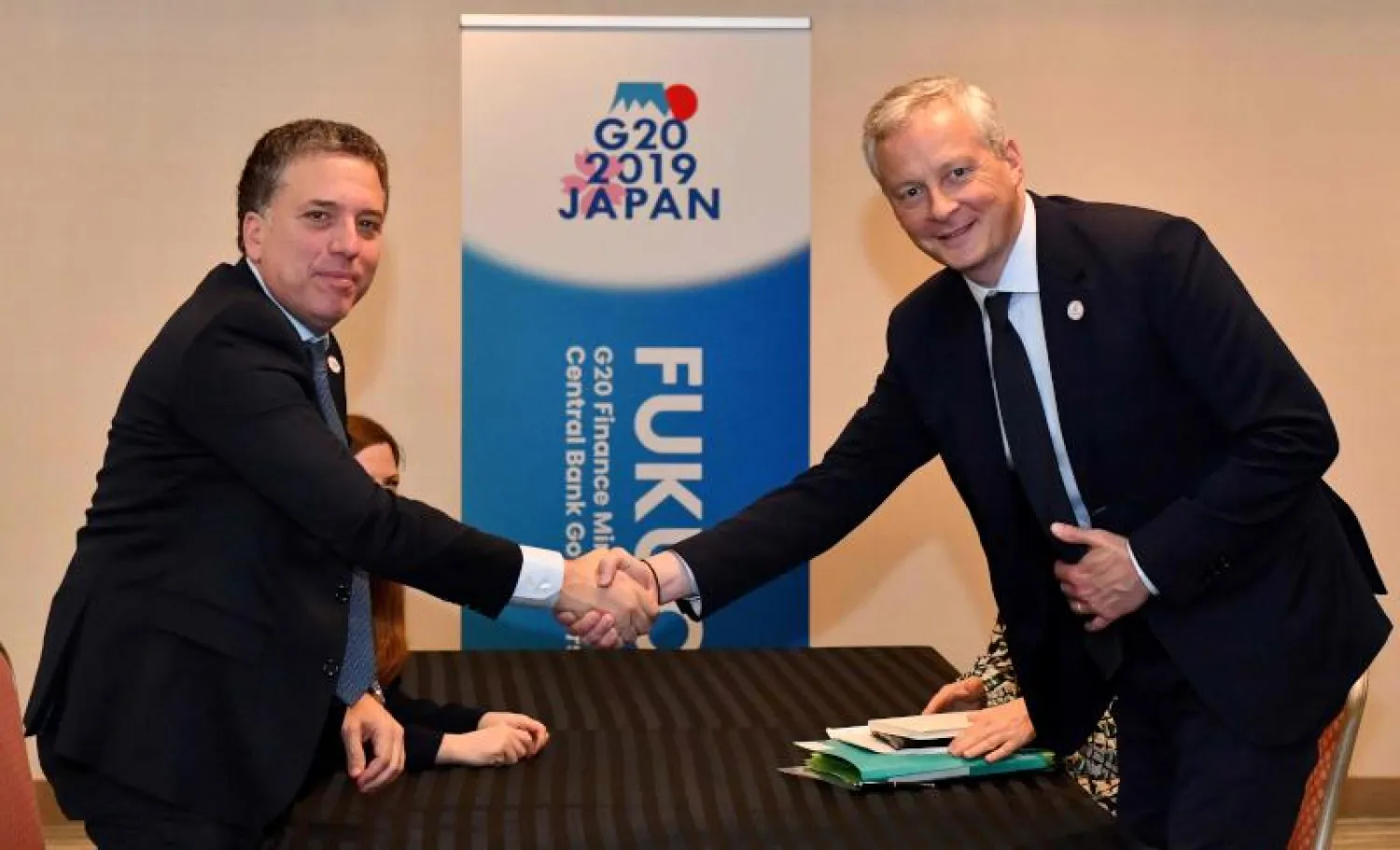 وزير الاقتصاد الفرنسي برونو لومير – إلى اليمين – يصافح وزير الخزانة الأرجنتيني نيكولاس دوجوفني في فوكوكا (أ. ف. ب)