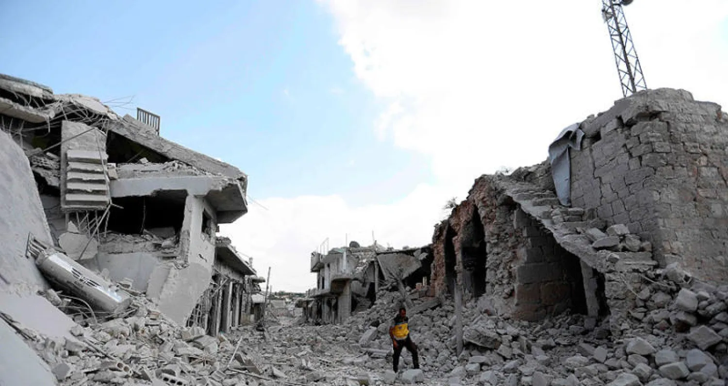 رجل يقف أمس بين أنقاض مبان مدمرة ببلدة إحسم في محافظة إدلب السورية (أ.ف.ب)